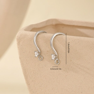 Detail of S-curve metal ear hooks with zircon hanging on a ceramic edge for DIY earrings