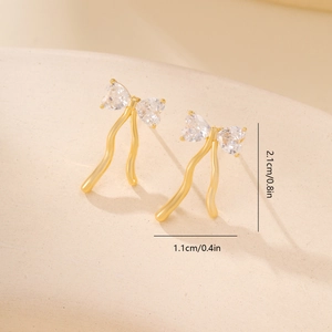 Detailed view of gold bow earrings with heart zircons and elegant flowing tassels