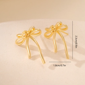 Detail view of gold bow earrings showing 2.3cm height and 1.8cm width with tiny crystal