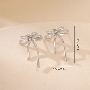 Detailed view of silver bow earrings with rose motif and 2.3cm by 1.8cm size measurements