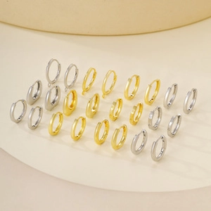 Detailed collection of assorted gold and silver hoop earrings on a minimalist round tray