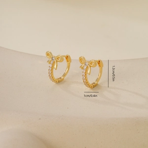 Detail van gouden strikoorbellen met zirkonia, hoogte 1,2 cm en breedte 1 cm
