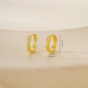 Detail of 1.2cm irregular twisted golden hoop earrings on a minimalist stone display