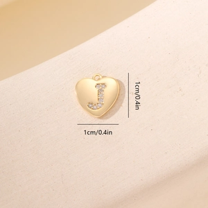 Dettaglio macro di un ciondolo a cuore dorato da 1cm con lettera J in zirconi