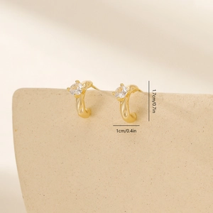 Macro detail of gold-plated geometric hoop earrings with sparkling cubic zirconia stones
