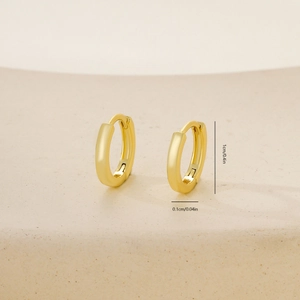 Detail view of 1cm polished gold huggie hoop earring on a beige display stand