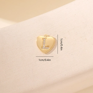 Pendente a cuore dorato con lettera L e zirconi scintillanti in primo piano macro