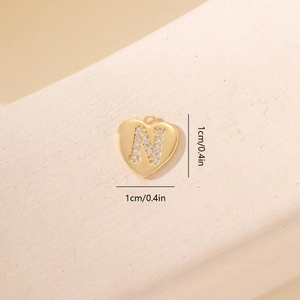 Dettaglio di ciondolo a cuore con lettera N in oro e zirconi, misura di 1 cm circa