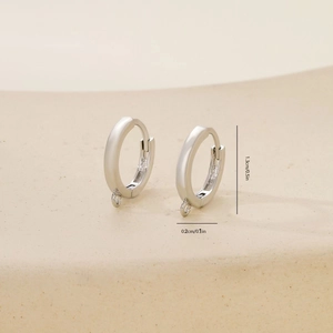 Detailed view of silver hoop earrings with size marks 1.3cm on elegant stone background