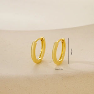 Close-up of golden huggie earrings with detailed dimensions of 1.1cm height and 0.2cm thickness