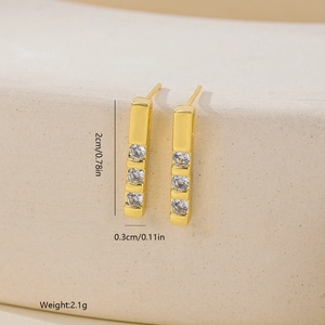 Macro detail of gold bar earrings with dimensions 2cm by 0.3cm and three cubic zirconia stones