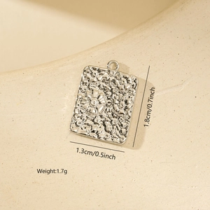 Detail view of square silver pendant with floral embossing and dimension labels