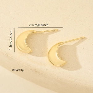 Detail shot of golden crescent stud earrings with 2.1cm length and polished metal finish