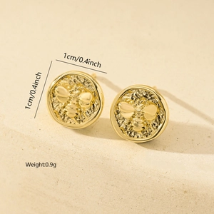 Detailed macro view of golden bee relief stud earrings with vintage coin texture