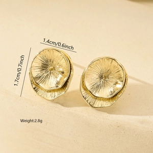 Macro detail of gold geometric earrings showing radiating textures and dimensions