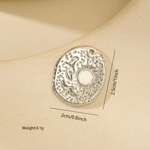 Detailed view of an oval metal pendant with sun and birds relief including size markings