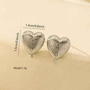 Macro detail of silver heart stud earrings featuring a liquid metal textured surface
