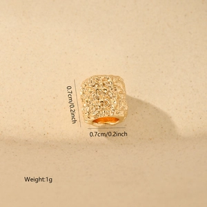 Detail shot of a 0.7cm gold cylinder bead with hammered texture and zircon inlay