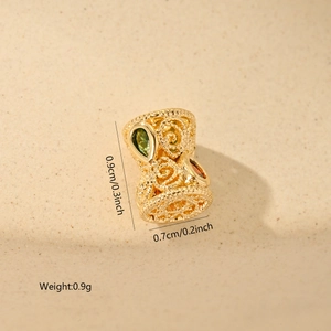 Detailed macro view of a gold hollow spacer bead with green zircon and spiral pattern