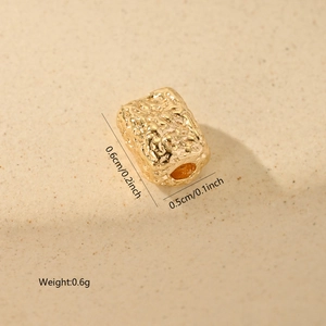 Close-up of golden geometric spacer bead with hammered texture and 0.6g weight