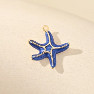Golden starfish pendant with blue enamel wave texture and zircon inlay on beige background