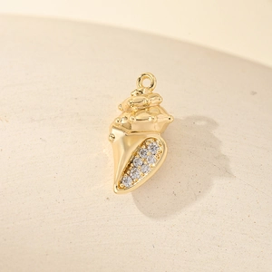 Golden conch pendant with sparkling zircons on textured stone surface for jewelry making