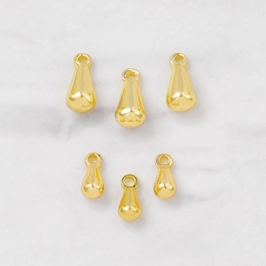 Gepolijste gouden druppelhangers voor DIY-sieraden op een witte marmeren achtergrond