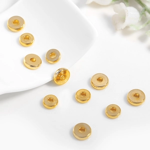 Cuentas espaciadoras planas de latón dorado para joyería DIY en una bandeja blanca