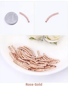 Detailed macro of rose gold textured curved tube beads with size reference coin