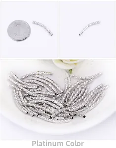 Macro detail of white gold curved spacer tube beads with diamond-cut texture for DIY jewelry