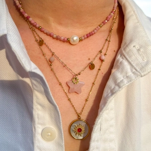 Close-up of three-layered gold necklaces with rhodochrosite stars and pearl charms