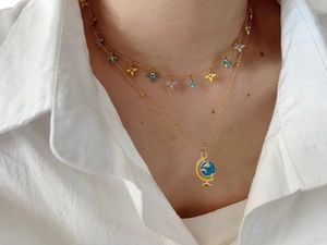 Detalle de collar dorado de varias capas con flores de esmalte y colgante de globo