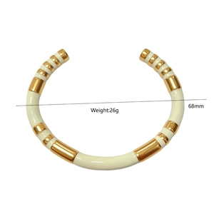 Detalle de brazalete en C de 68mm bañado en oro con incrustación de esmalte crema