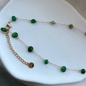 Détail de la chaîne dorée en acier inoxydable avec perles en pierre naturelle verte