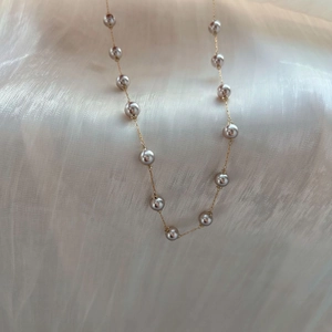 Gros plan détaillé d'un collier de perles gris-violet avec chaîne en or sur soie