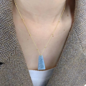 Golden beaded chain necklace featuring a geometric blue trapezoid natural stone pendant