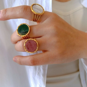 Three gold-plated rings with natural stone inlays worn on fingers, retro style jewelry