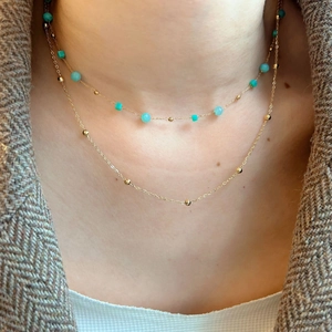 Double-layered gold necklace with turquoise beads and Amazonite pendant on a blazer
