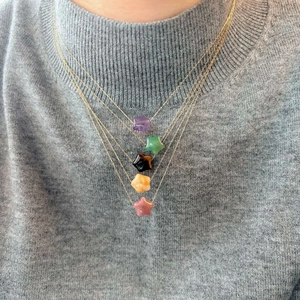 Star-shaped natural stone pendants on gold necklaces worn by a model in a layered style