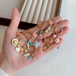 Golden titanium steel earrings with ocean charms like sea shells and stars on a tray