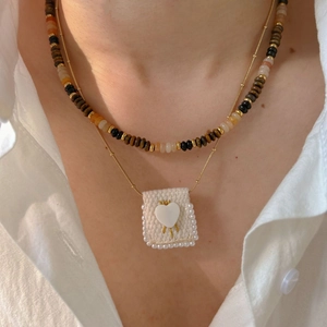 Layered gold necklace with brown stone beads and a pearl-bordered heart square pendant