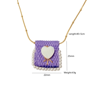 Detail of a purple knitted bag pendant necklace with white heart and faux pearls