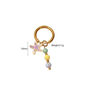Détail des boucles d'oreilles dorées avec pendentif étoile de mer et perles pastel