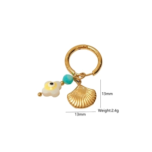 Détail de boucles d'oreilles coquillage doré avec perle fleur et pierre turquoise