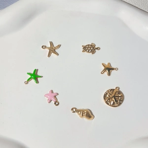 Gold-plated starfish and turtle charms set for DIY jewelry on white ceramic plate