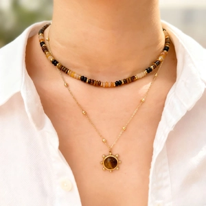 Double-layered tiger eye stone beaded necklace set with sunburst pendant on white shirt