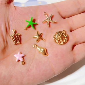 Golden stainless steel starfish and sea creature pendants held in palm for DIY jewelry