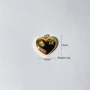 Detail showing 15mm heart pendant size with green stones and polished gold finish