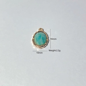 Detail view of oval turquoise pendant with 18mm height and engraved gold plated base