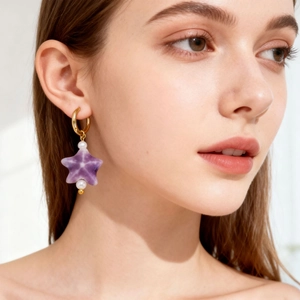 Gold hoop earrings featuring purple star amethyst and white pearls on a model